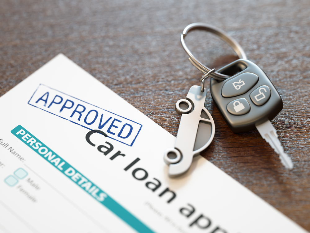 Approved car loan form with car keys on a wooden surface