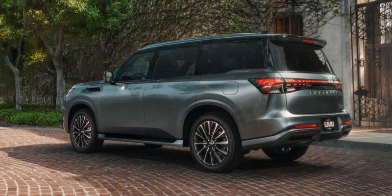 Gray INFINITI QX80 SUV parked on a brick driveway.