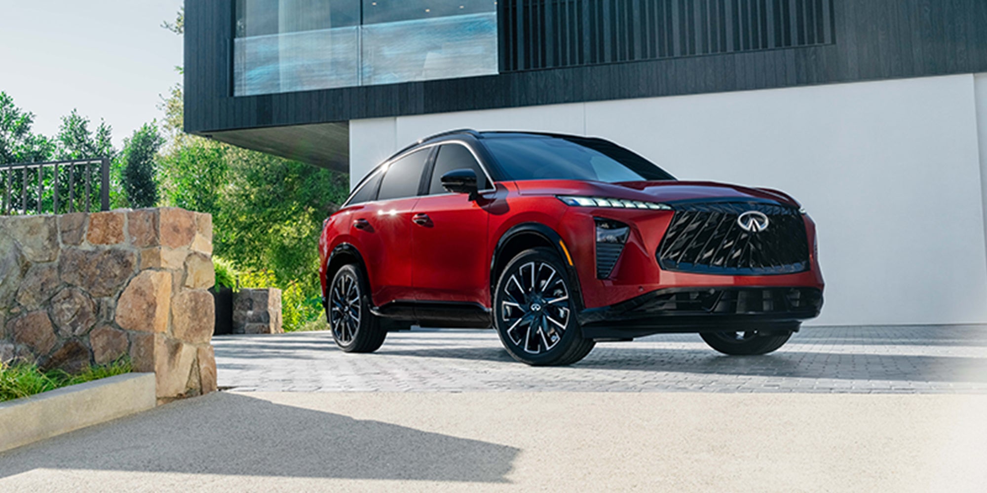Red 2027 INFINITI QX65 SUV parked outside a modern home.